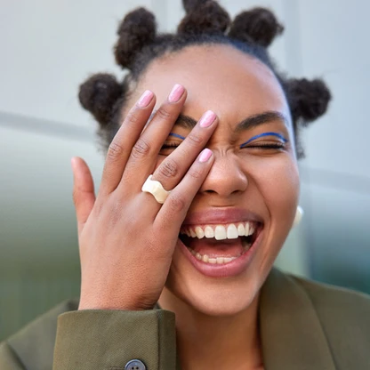woman-smiles-broadly-shows-white-teeth-makes-face-palm-being-amused-by-someone-has-bun-hai